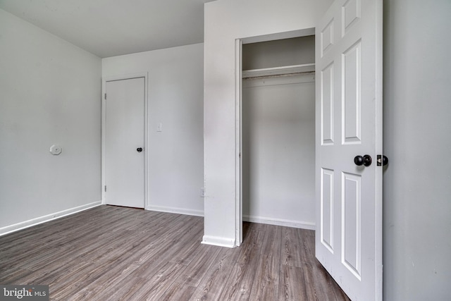 unfurnished bedroom featuring a closet, baseboards, and wood finished floors