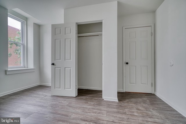 unfurnished bedroom featuring a closet, baseboards, and wood finished floors