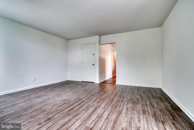 unfurnished room featuring baseboards and dark wood finished floors