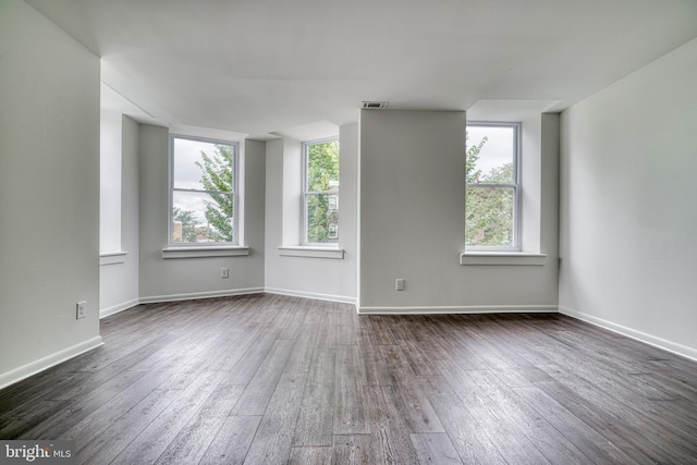 unfurnished room featuring dark wood-style floors, visible vents, and baseboards