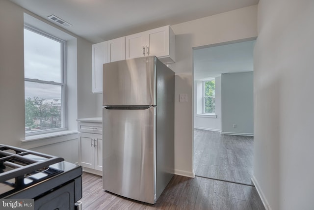 kitchen featuring freestanding refrigerator, white cabinets, visible vents, and hardwood / wood-style floors