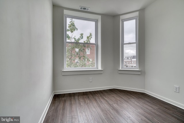 spare room with baseboards, visible vents, and dark wood-type flooring