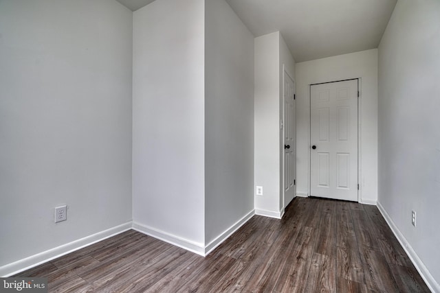 spare room featuring dark wood-type flooring and baseboards