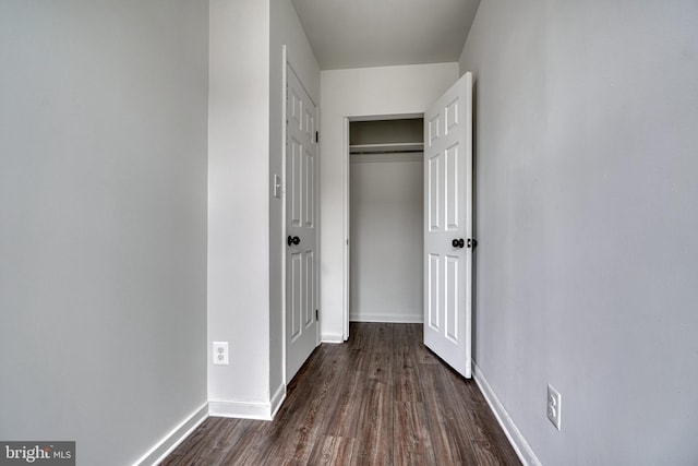 hallway featuring dark wood-type flooring and baseboards