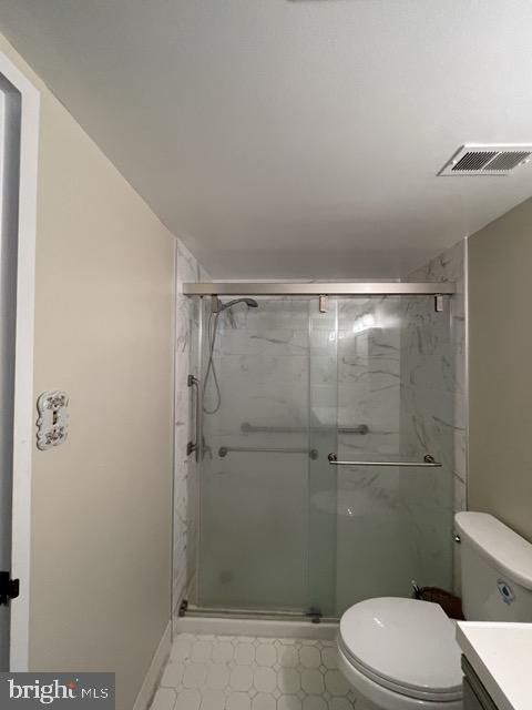 full bath featuring toilet, vanity, visible vents, and a shower stall