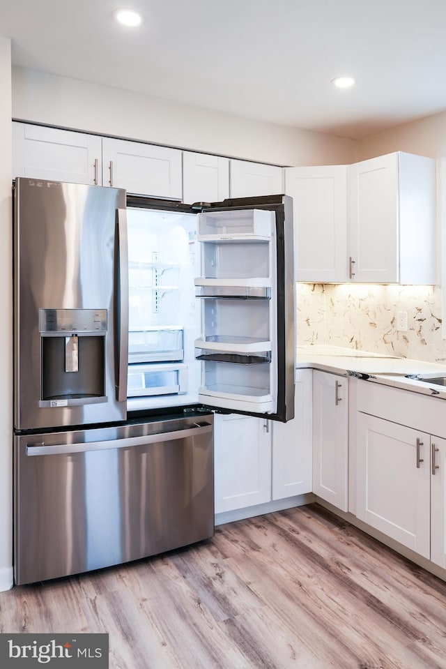 kitchen with decorative backsplash, white cabinets, and light hardwood / wood-style flooring