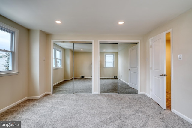 unfurnished bedroom with carpet floors and two closets