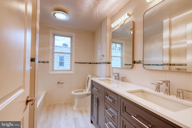 bathroom with tile walls, vanity, hardwood / wood-style floors, and toilet