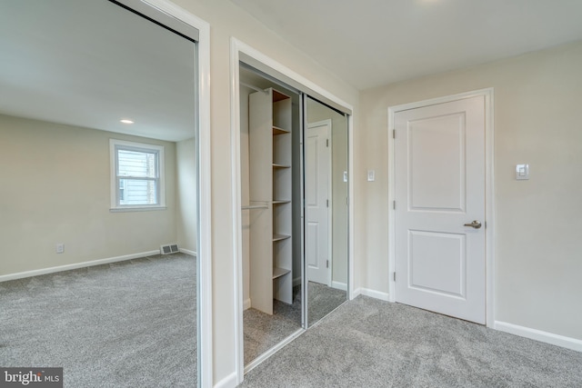 unfurnished bedroom with light colored carpet and a closet