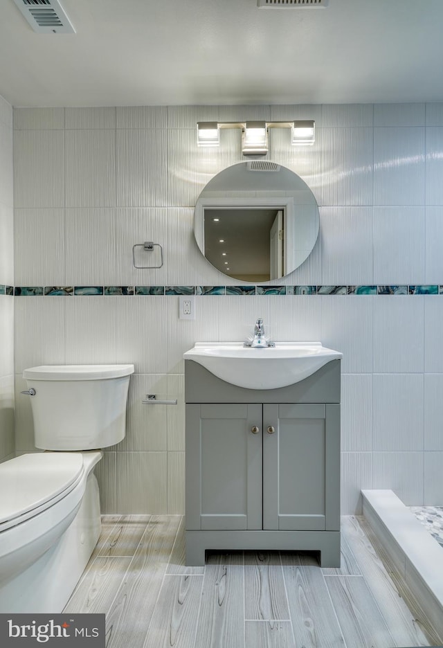 bathroom featuring vanity, toilet, and tile walls