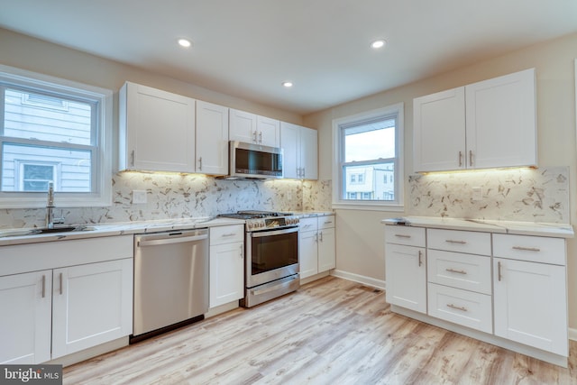 kitchen featuring white cabinetry, appliances with stainless steel finishes, light hardwood / wood-style floors, and sink