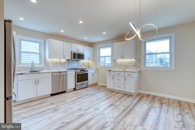 kitchen featuring white cabinetry, appliances with stainless steel finishes, sink, and pendant lighting