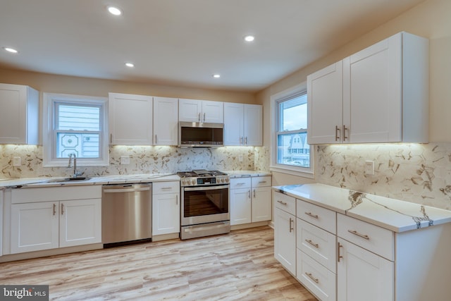 kitchen featuring white cabinetry, appliances with stainless steel finishes, sink, and light hardwood / wood-style flooring