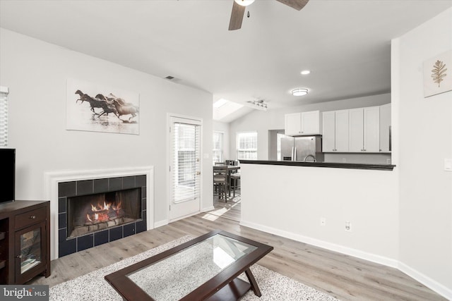 living room with visible vents, vaulted ceiling, light wood-style flooring, and baseboards