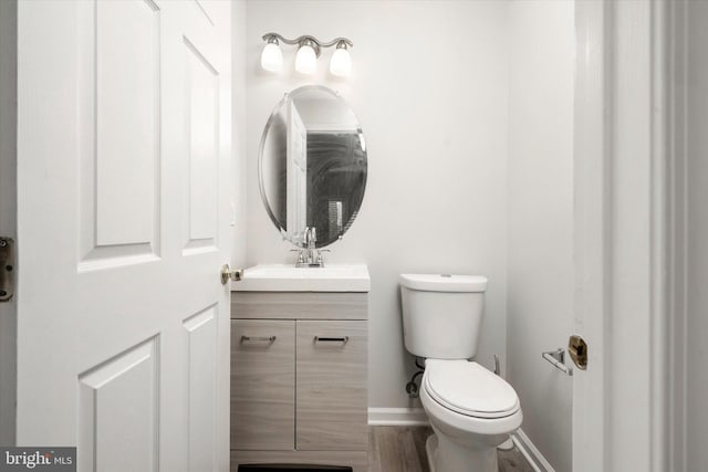 bathroom with toilet, baseboards, and vanity