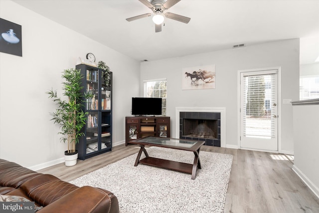 living area featuring light wood finished floors, baseboards, visible vents, and a tile fireplace