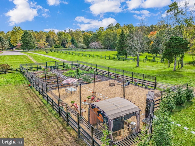 view of community featuring a yard, fence, an outdoor structure, and a rural view