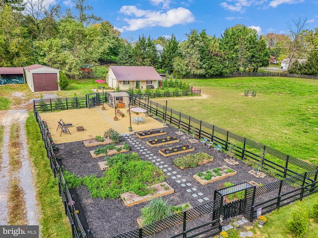 view of yard with a rural view, a garage, an outdoor structure, fence, and a vegetable garden