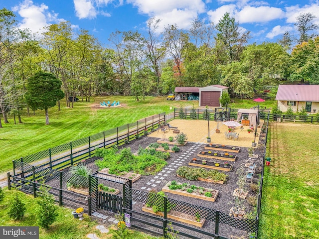 view of property's community with a yard, a vegetable garden, an outdoor structure, and fence