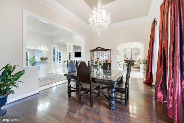 dining room featuring arched walkways, ornamental molding, a chandelier, and dark wood-style floors