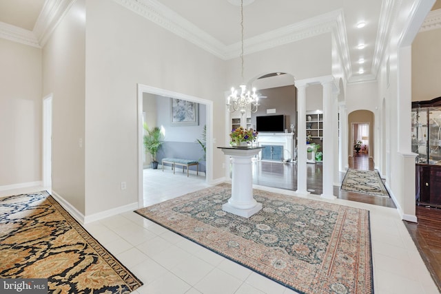 foyer entrance with ornamental molding, arched walkways, a towering ceiling, and ornate columns