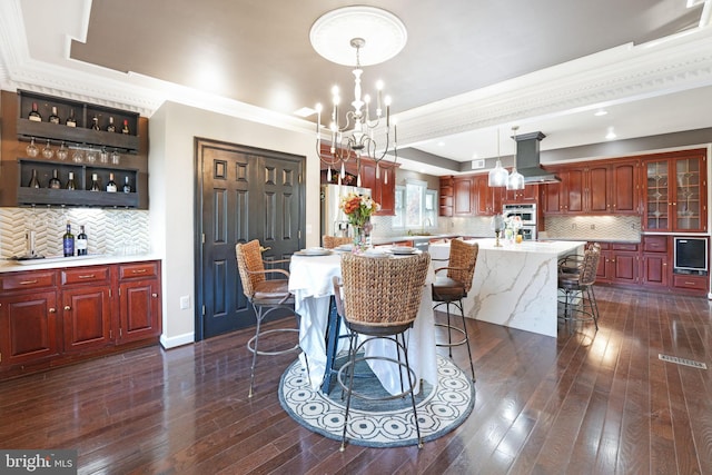 dining room with a chandelier, baseboards, a tray ceiling, dark wood finished floors, and crown molding