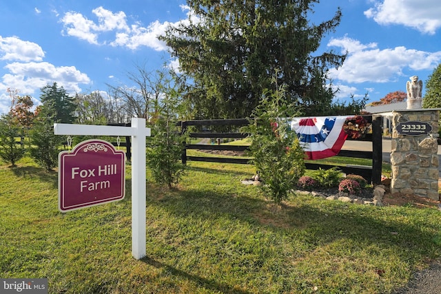 community / neighborhood sign with a yard and fence