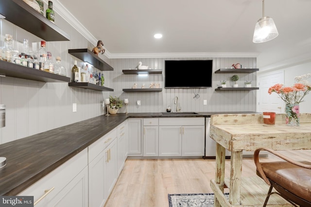 bar with light wood-style floors, wet bar, ornamental molding, and a sink