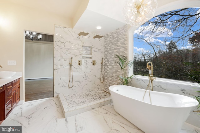 bathroom with a chandelier, marble finish floor, a freestanding bath, and vanity