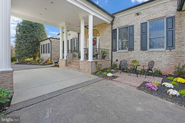 property entrance featuring covered porch and brick siding