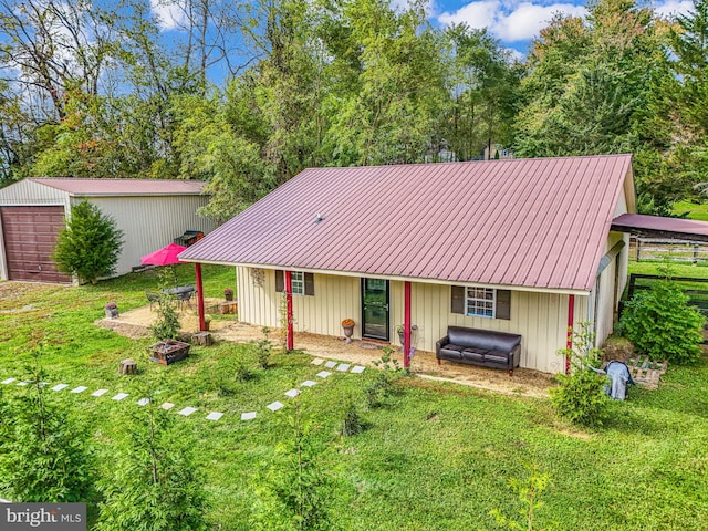 view of front of home with an outbuilding, a front yard, metal roof, a garage, and a fire pit