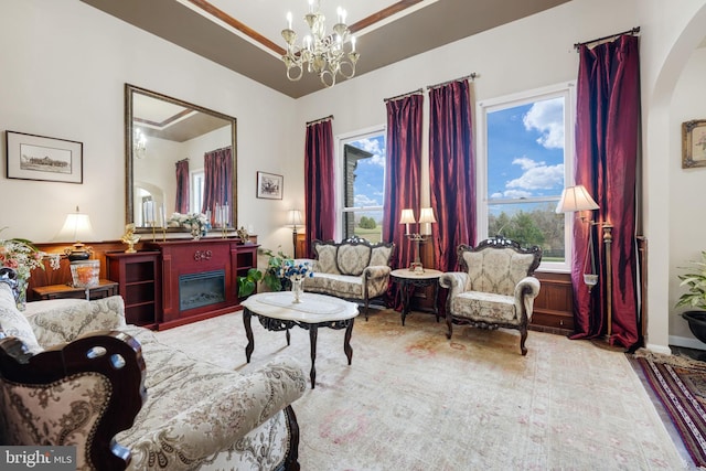 sitting room featuring arched walkways, a glass covered fireplace, and a notable chandelier