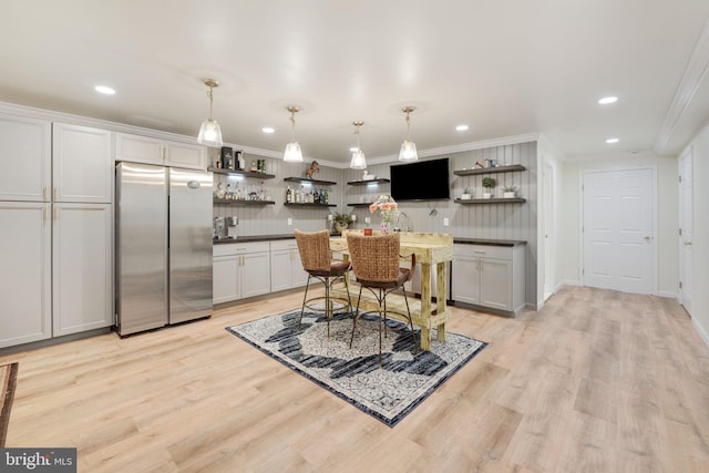 kitchen with dark countertops, open shelves, crown molding, and freestanding refrigerator