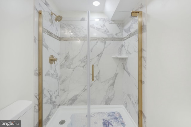 bathroom featuring toilet and a marble finish shower