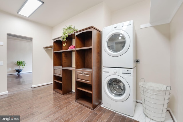 laundry room with laundry area, baseboards, wood finished floors, and stacked washer and clothes dryer