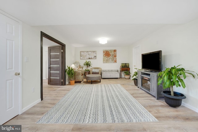 living area featuring baseboards and light wood finished floors