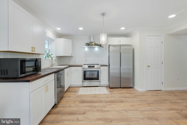 kitchen with light wood-style flooring, appliances with stainless steel finishes, white cabinets, and a sink