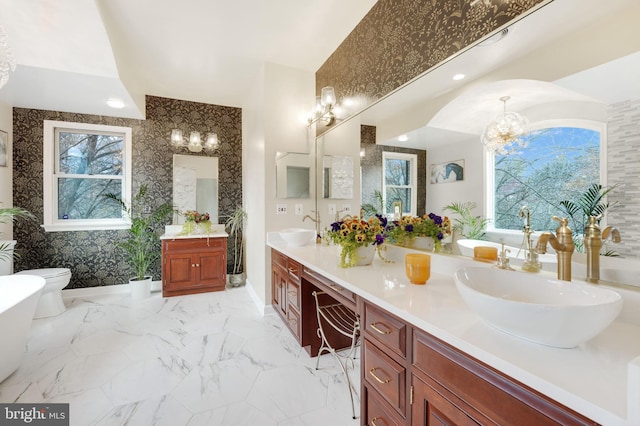 bathroom featuring a chandelier, marble finish floor, a sink, and double vanity