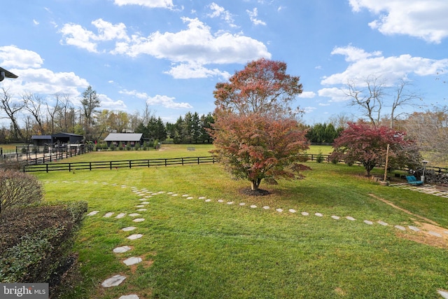 view of yard featuring fence, a pole building, an outbuilding, and a rural view