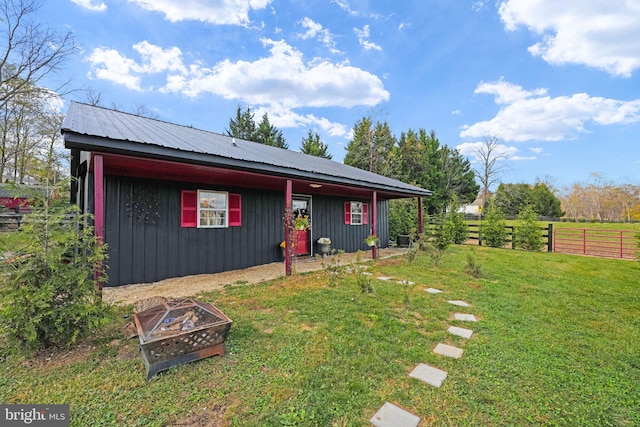 view of front of house featuring a fire pit, metal roof, a front lawn, and fence