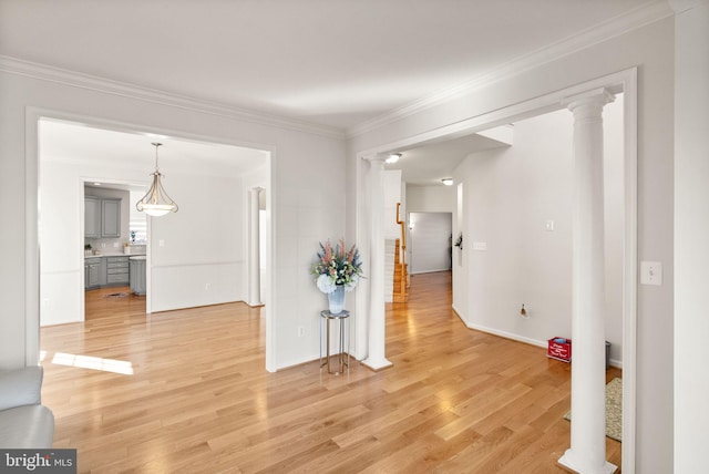 hallway featuring baseboards, decorative columns, ornamental molding, and wood finished floors