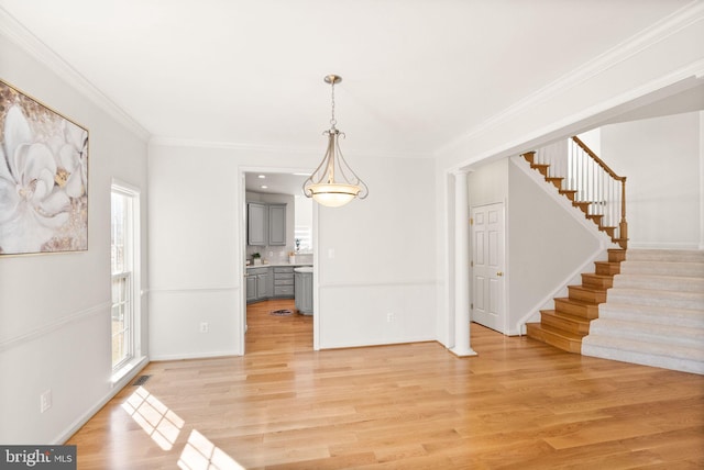 unfurnished dining area with light wood-style floors, stairs, visible vents, and crown molding