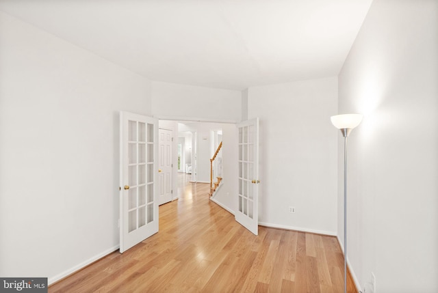 hall featuring light wood finished floors, french doors, and baseboards