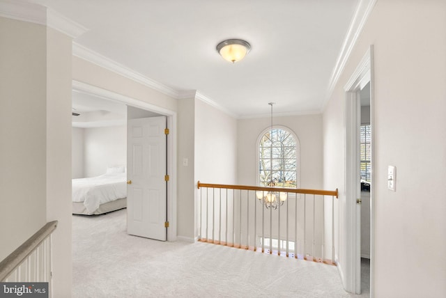 hall with a chandelier, light carpet, and ornamental molding