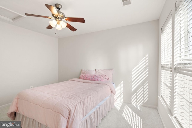 bedroom with a ceiling fan, attic access, and light colored carpet