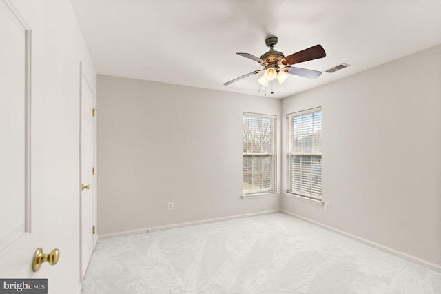 empty room featuring light carpet, visible vents, baseboards, and a ceiling fan