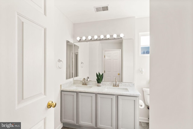 full bath featuring toilet, double vanity, a sink, and visible vents