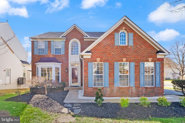 traditional-style home with central AC unit and brick siding