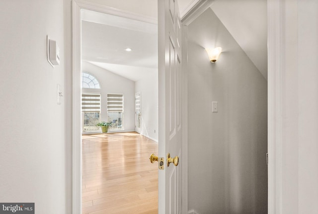 hallway featuring light wood finished floors and vaulted ceiling