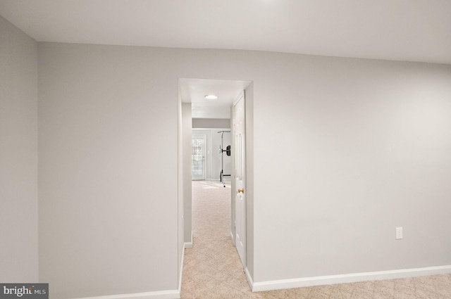 corridor with baseboards and light colored carpet